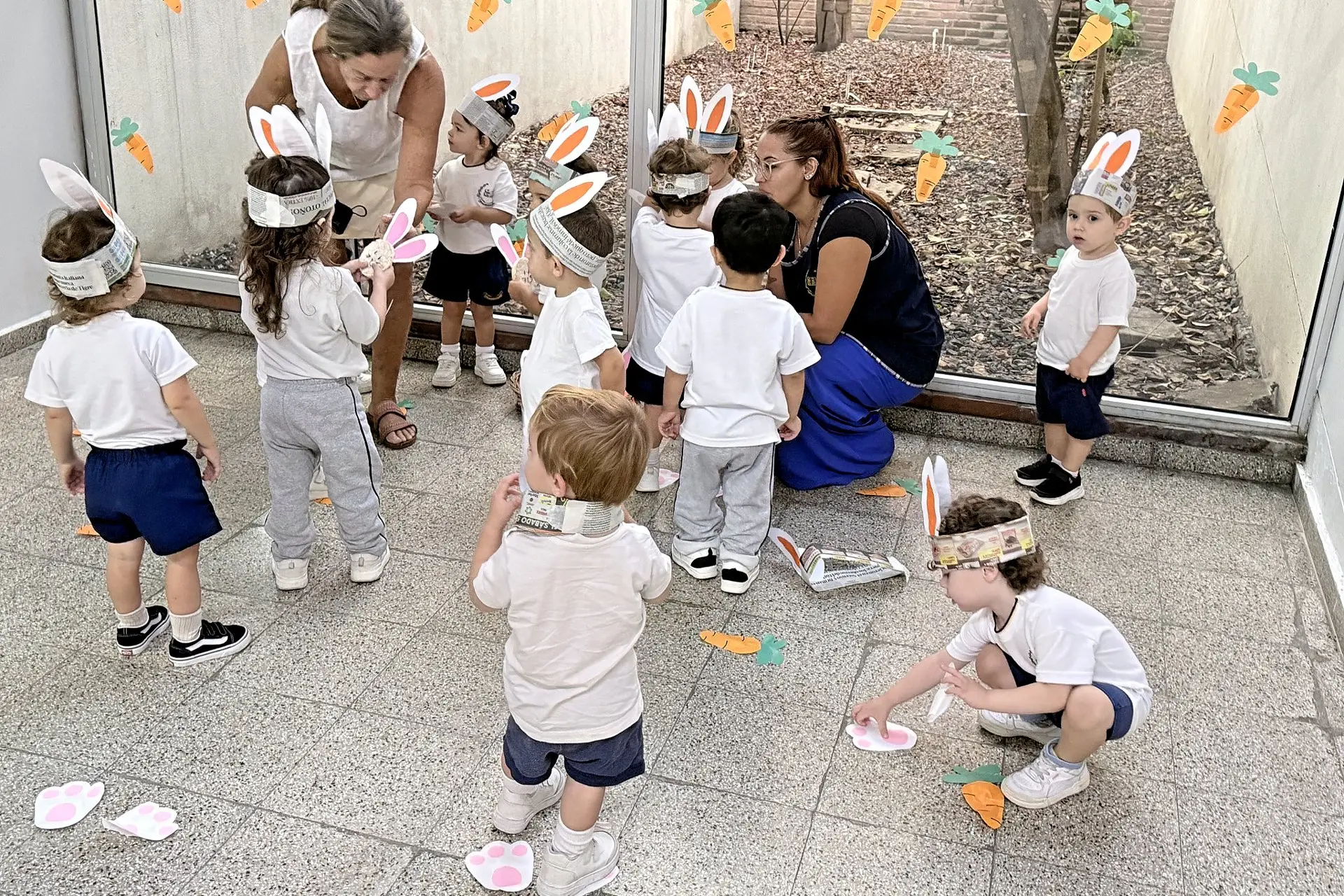 Niños de nivel inicial con orejas de conejo jugando junto a sus docentes en la celebración de Pascua