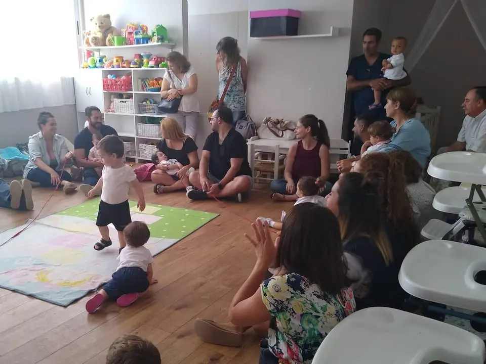 Familias y bebés compartiendo una actividad de juego en la sala de maternal