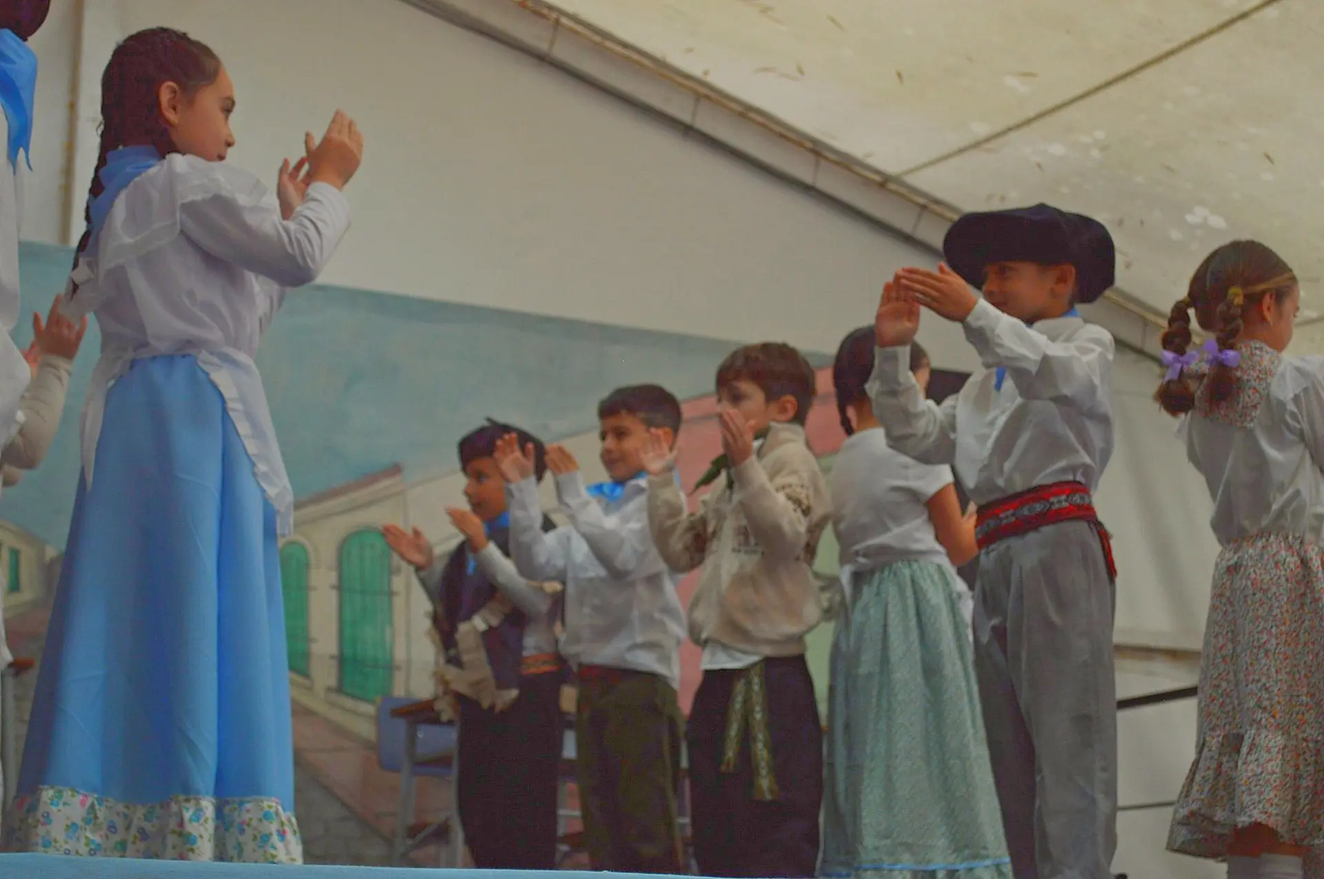 Alumnos de primaria con trajes típicos bailando en un acto escolar