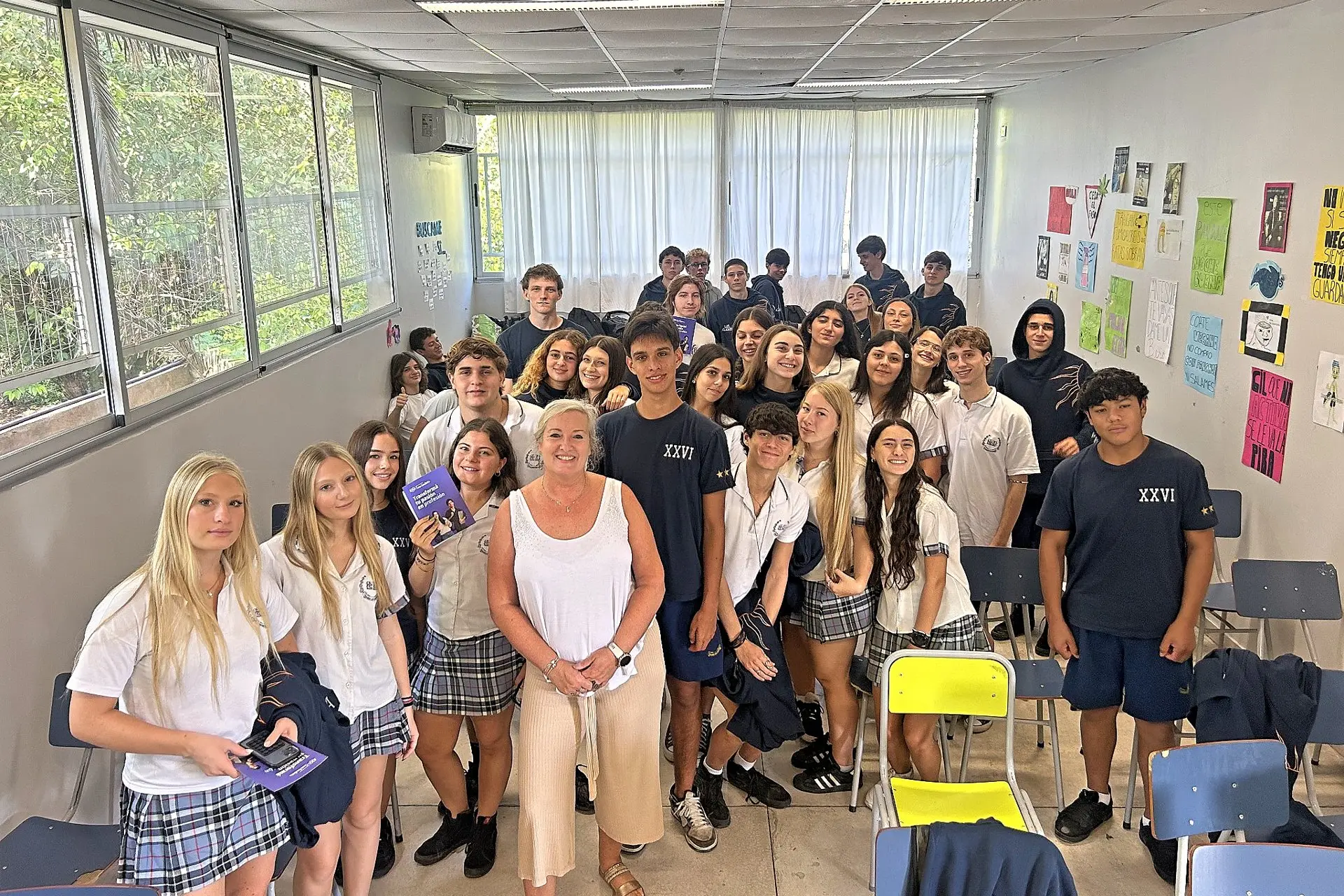 Grupo de estudiantes de secundaria reunidos en el aula junto a una docente