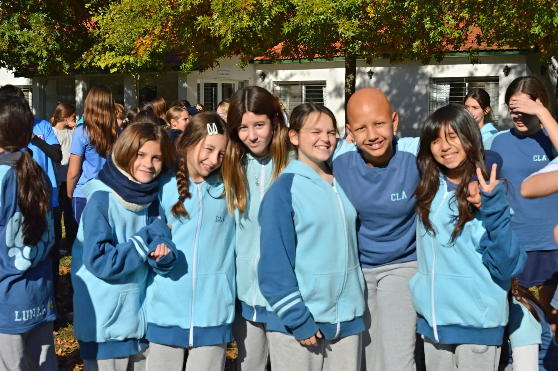 Grupo de alumnas de secundaria sonriendo con las camperas del colegio